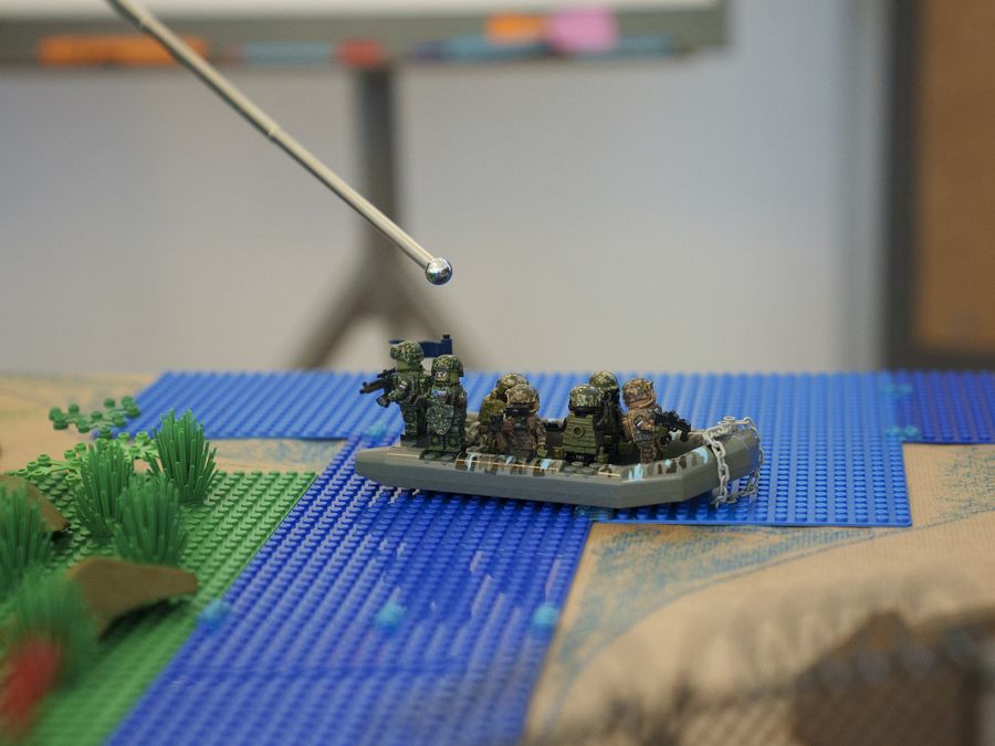 Ein Zeigestock über einem Schlauchboot mit Figuren: Die Lage wird am Modell erklärt